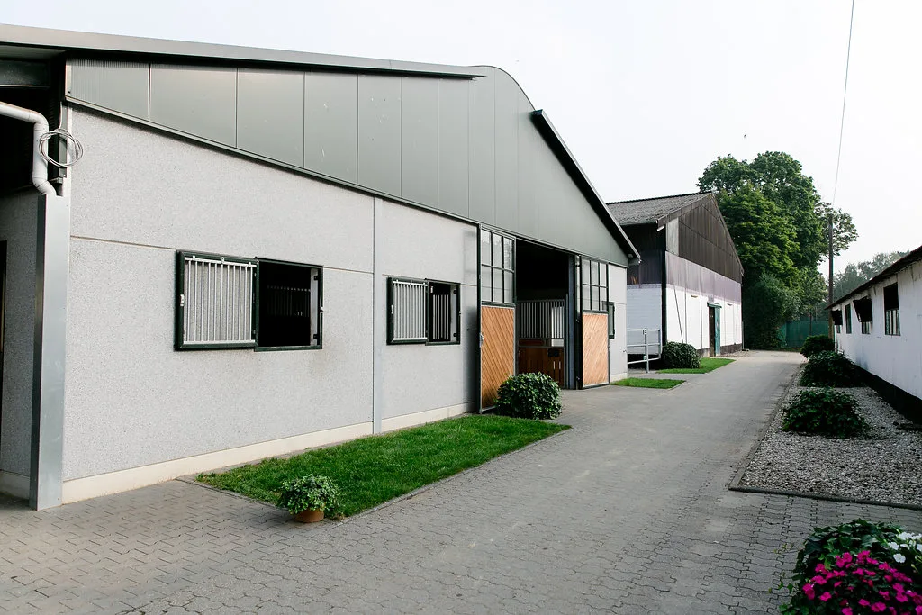 Die Reithalle des Reitstalls Pulheim von außen, davor die Stallgasse